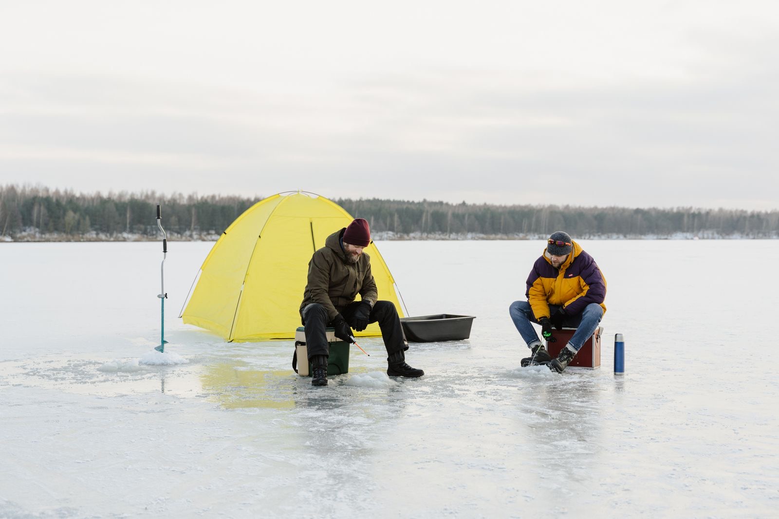Two anglers jigging beside a tent on the ice