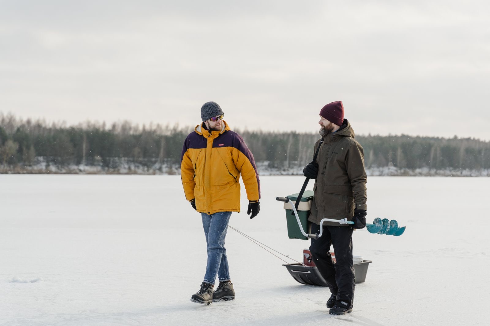 Two anglers walking gear out onto a frozen lake